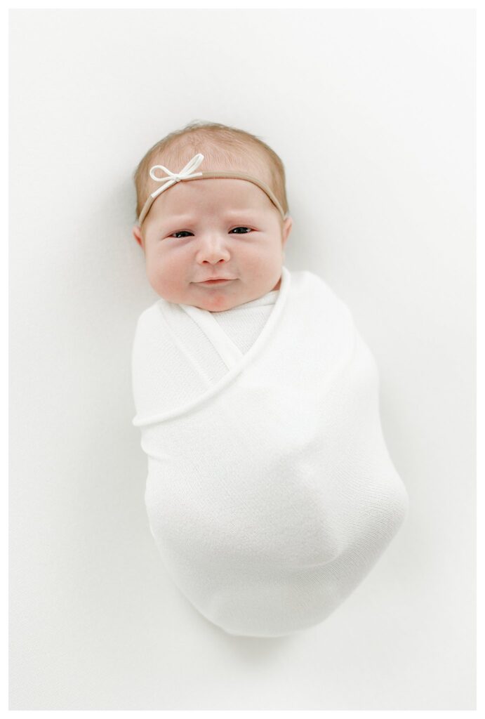 baby girl swaddled in a white blanket during her Charleston Newborn Session