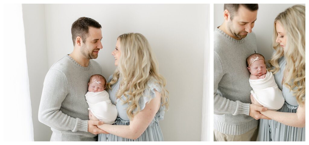 Mom and dad standing and holding their babygirl in a natural light studio captured by Philadelphia Newborn Photographer Tara Federico