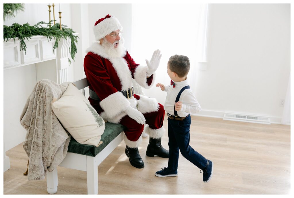 A little boy high fives Santa who looks very excited during their South Jersey Santa Pictures