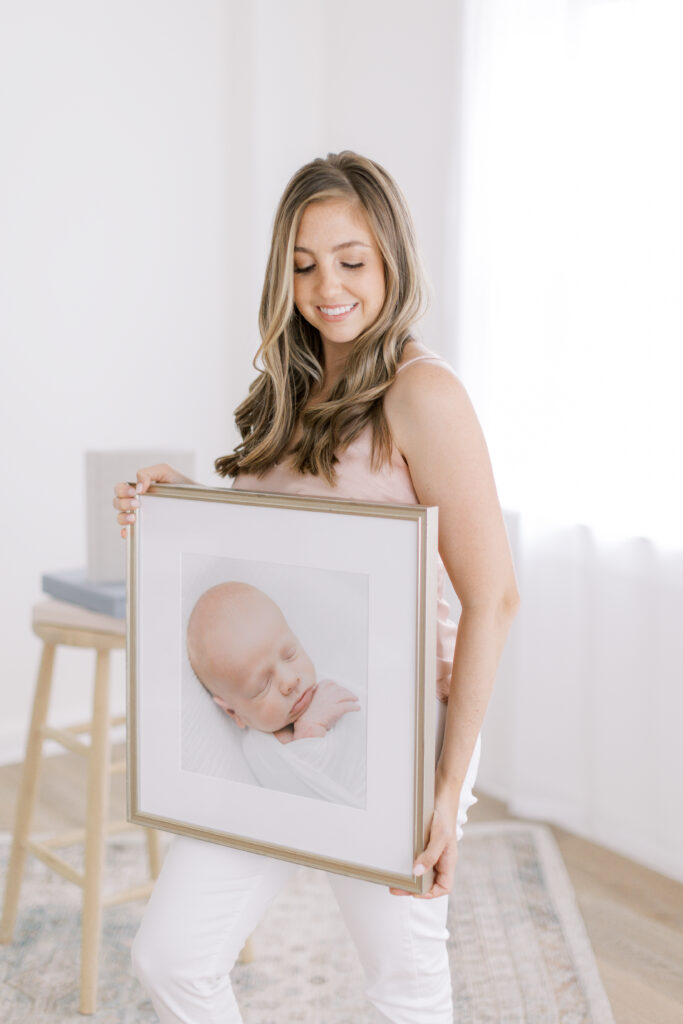 Charleston newborn photographer displaying framed portraits of a newborn baby