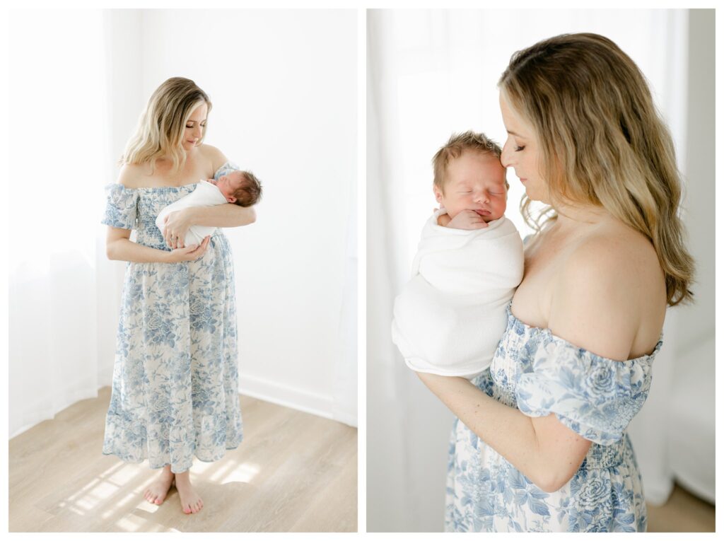 Mother holding her newborn baby boy wrapped in a white swaddle during a Charleston newborn session prep, with mom wearing a white and blue floral off-the-shoulder dress.